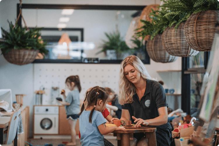 Childcare worker and child sitting at table