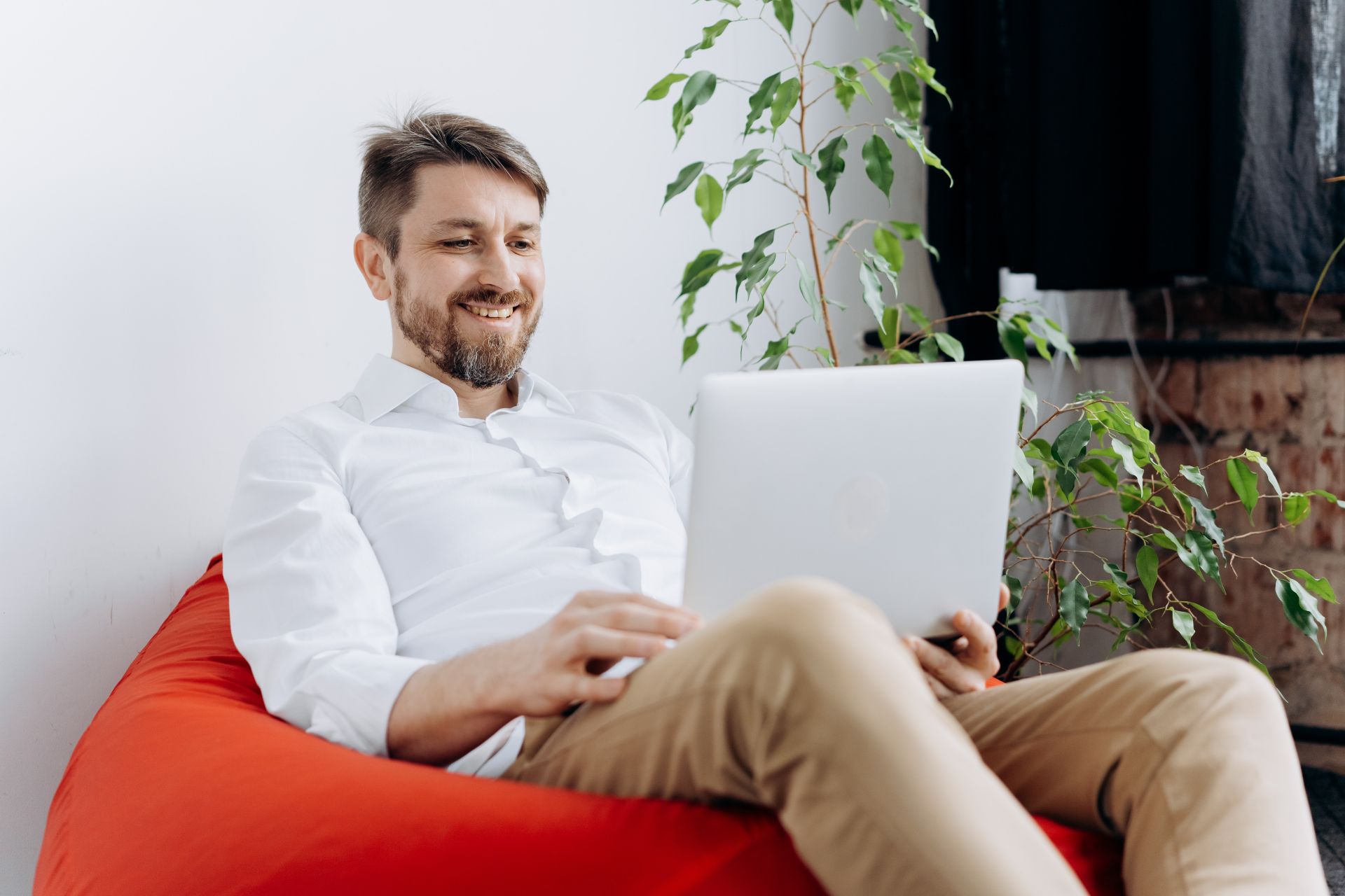 Man on computer on bean bag reading tips for perfect employee schedules