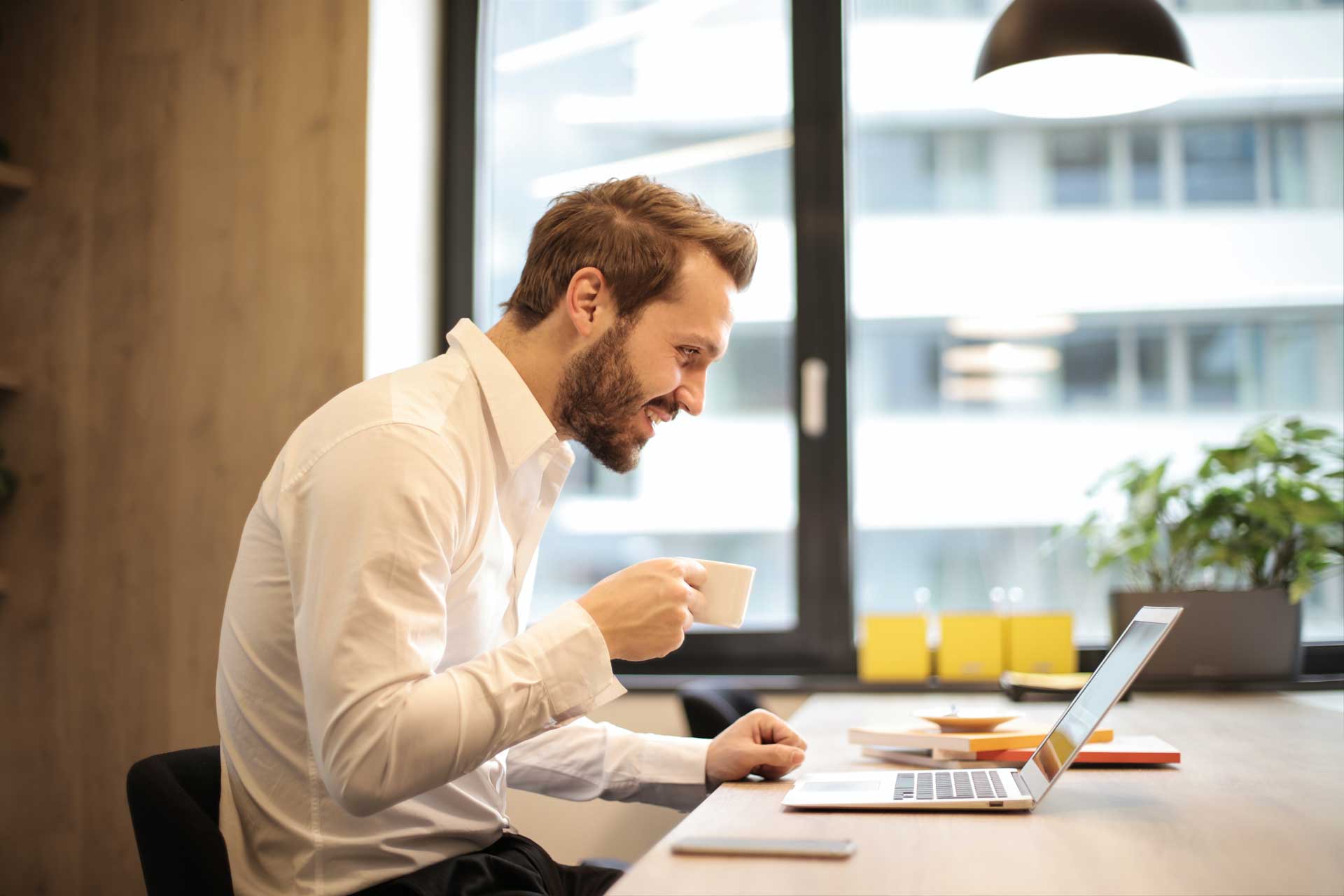 Man reviewing digital timesheets and payroll with coffee